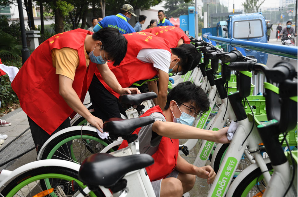 世界無(wú)車日，志愿者走上街頭擦亮共享助力車